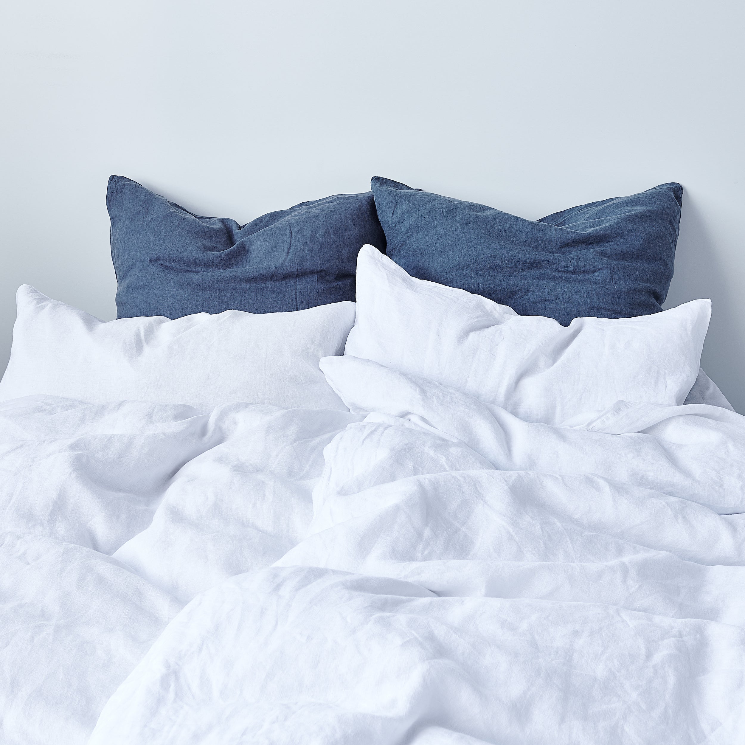 Leinen-Kissenbezug Atlantikblau auf einem Bett mit weißen und blauen Kissen, ideal für eine stilvolle Raumgestaltung.