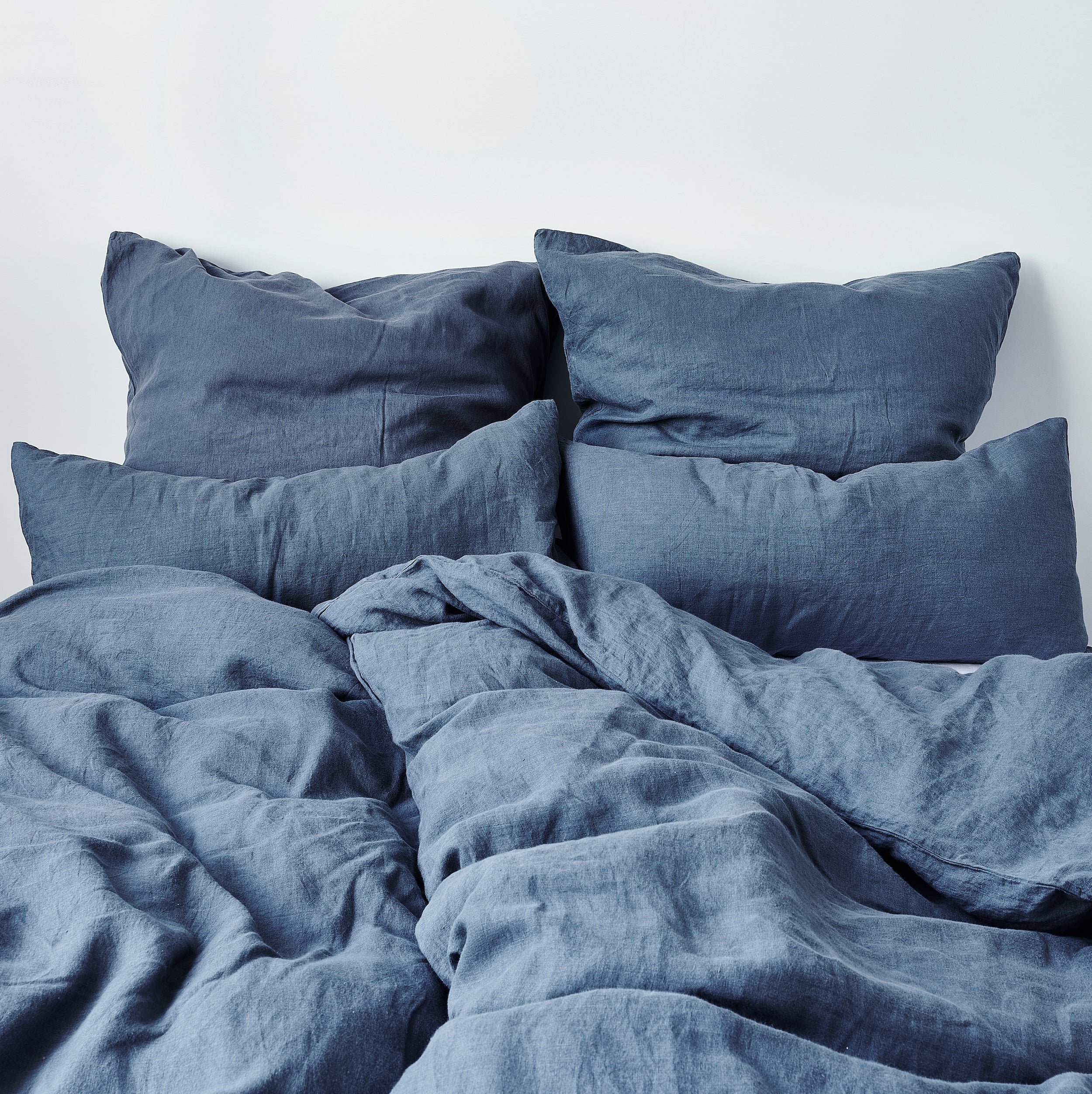 Leinen-Kissenbezug Atlantikblau auf Bett mit weichen Kissen aus 100% Leinen, hochwertig und bequem.