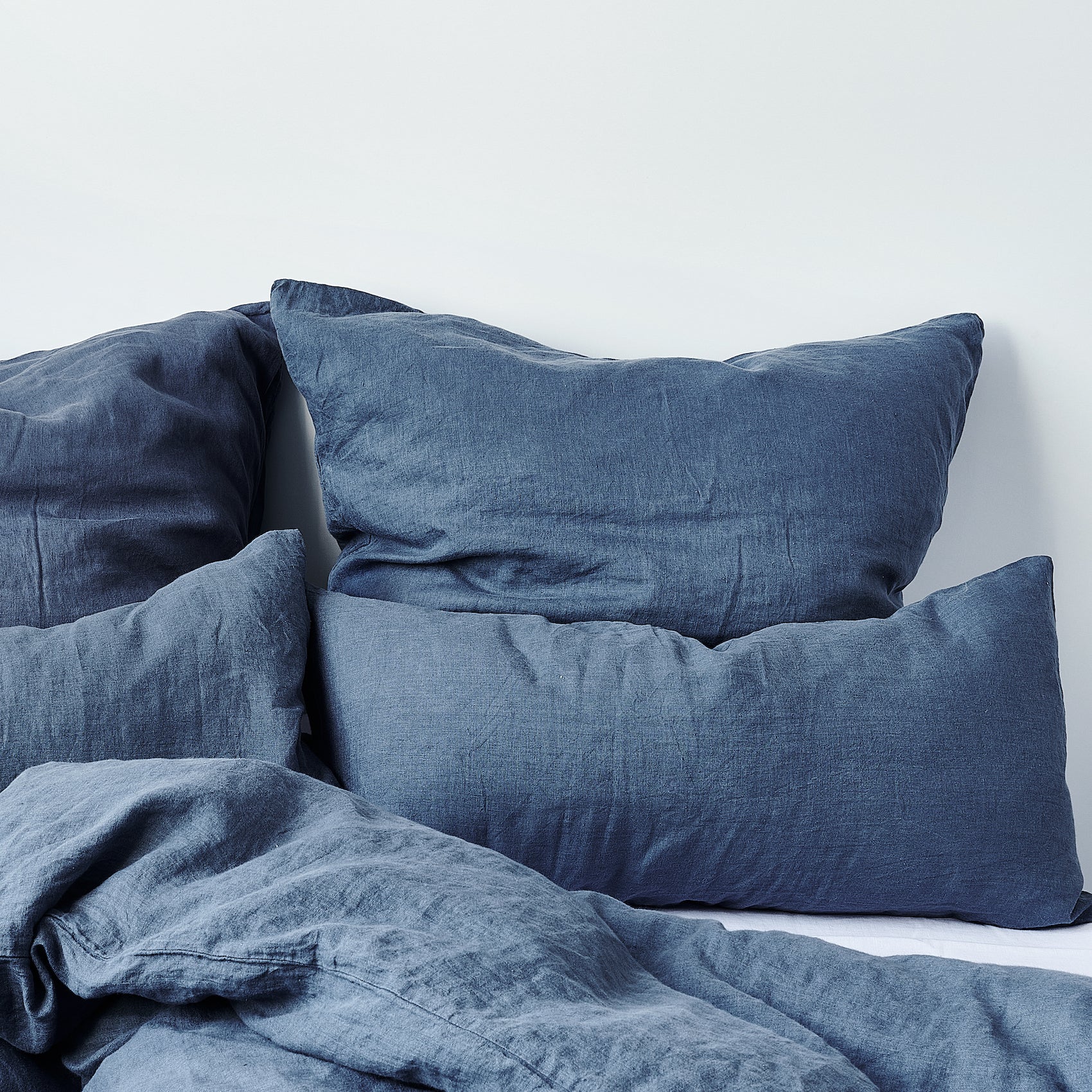 Leinen-Kissenbezug Atlantikblau auf Kissen im gemütlichen Schlafzimmer-Design.