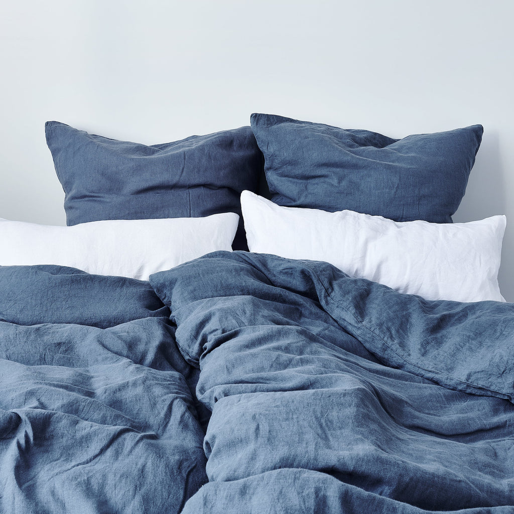 Leinen-Deckenbezug Atlantikblau auf einem Bett mit weißen und blauen Kopfkissen.