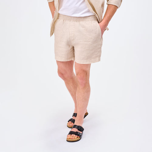 Leinen Shorts Herren Sand in beigem Farbton, lässig gestylt mit schwarzen Sandalen für warmes Wetter.